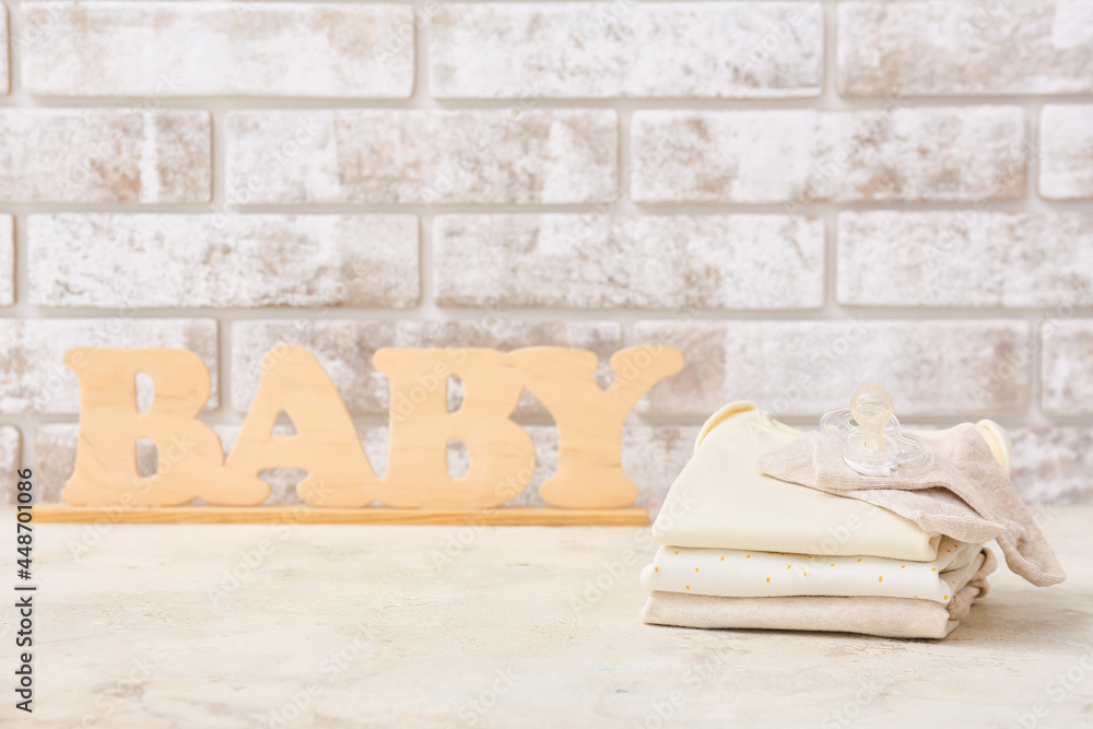 靠砖墙的桌子上放着一套婴儿饰品和木制单词baby