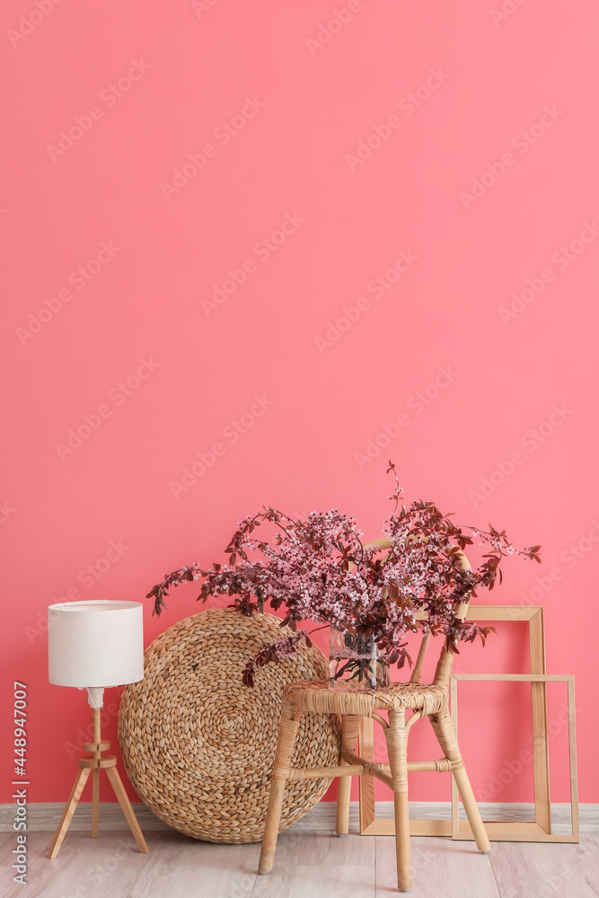 彩色墙附近椅子上的花瓶，树枝开花