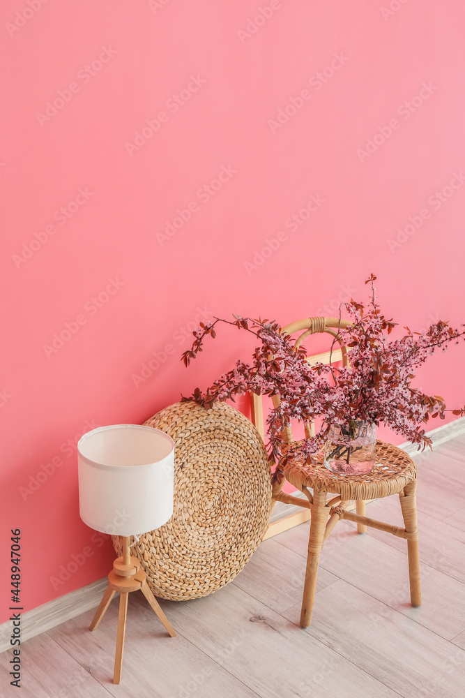 靠近彩色墙的椅子上有开花树枝的花瓶