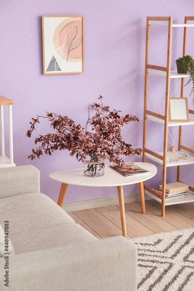 彩色墙壁附近桌子和书架上的花瓶上有朵朵树枝