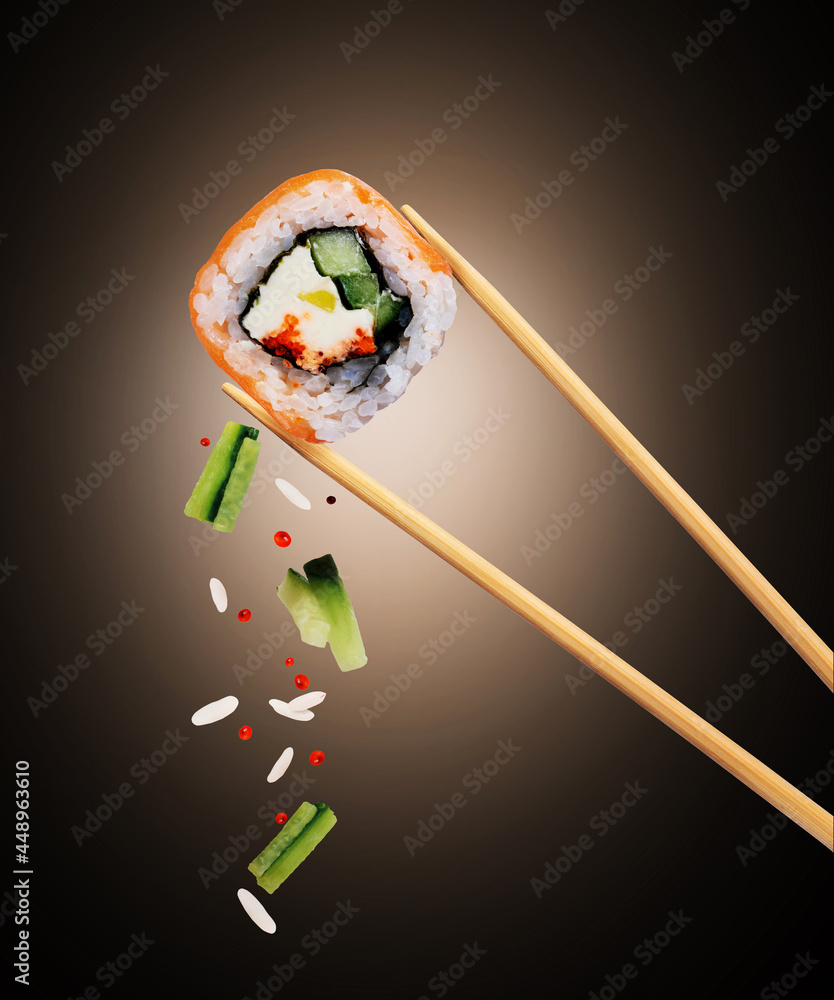 Fresh traditional japanese sushi with salmon and caviar between chopsticks on black background