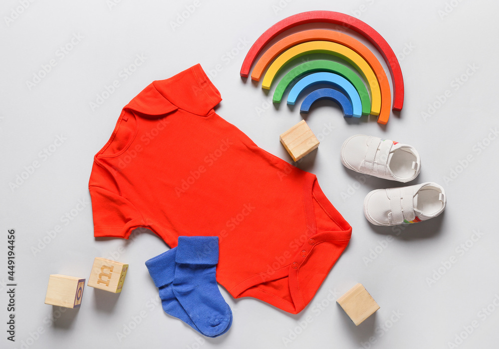 Baby clothes, shoes and toys on light background