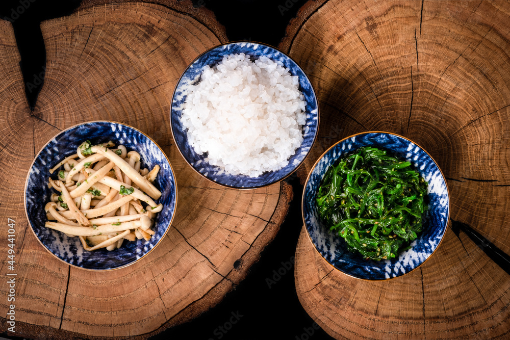 木桌背景碗中的白taki米饭或面条、shimeji蘑菇和wakame。Konnyaku