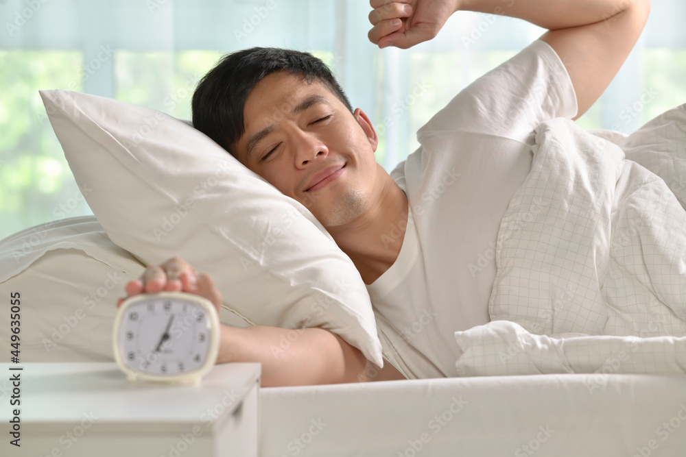 早上在床上醒来的快乐亚洲男人的肖像