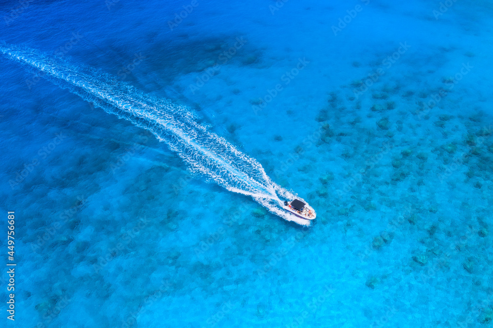 Aerial view of the speed boat in clear blue water at sunset in summer. Top view from drone of fast f
