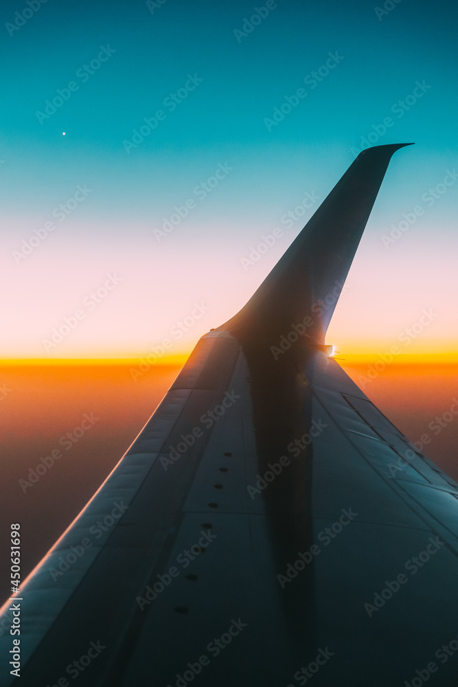 飞机机翼上的近景。日落天空下的飞机。高空飞行O时从飞机窗口观看