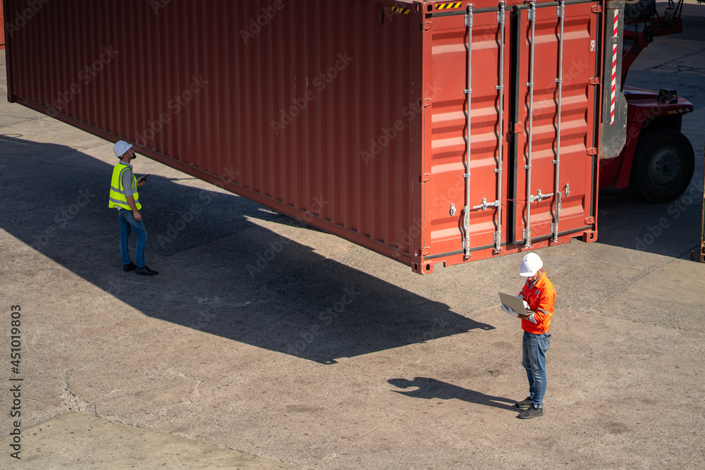 工程师正在监督仓库内集装箱货物的运输。集装箱