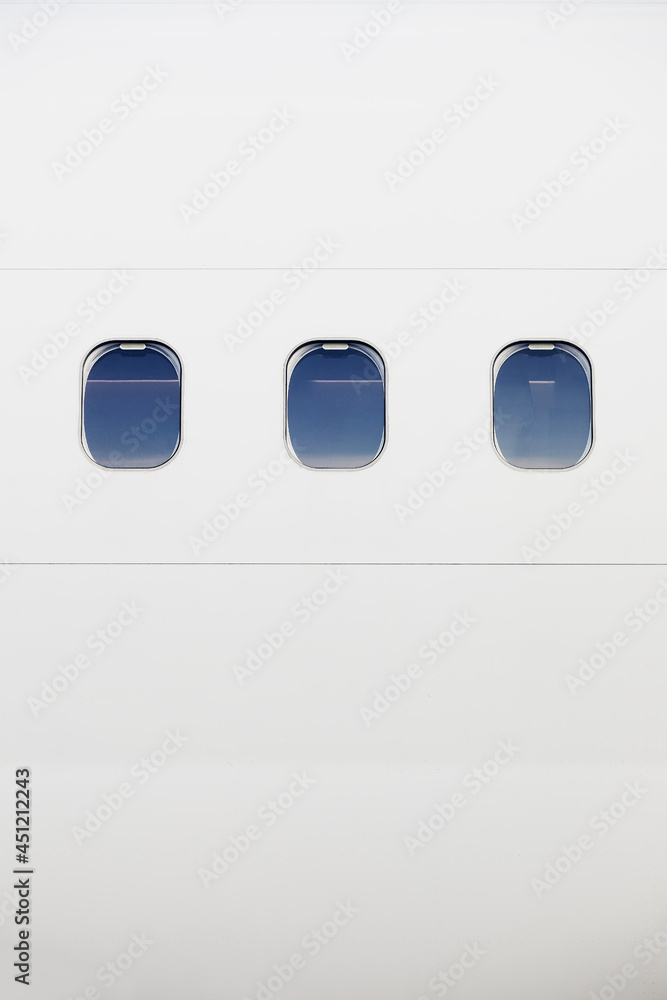 白色飞机机身上的三个窗口。带有复制空间的飞机垂直图像。