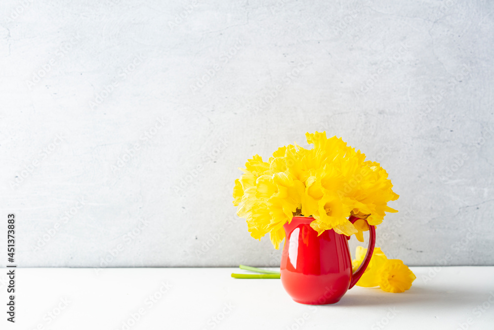 桌面上一个红色罐子里的黄色水仙花花束，家居装饰，室内