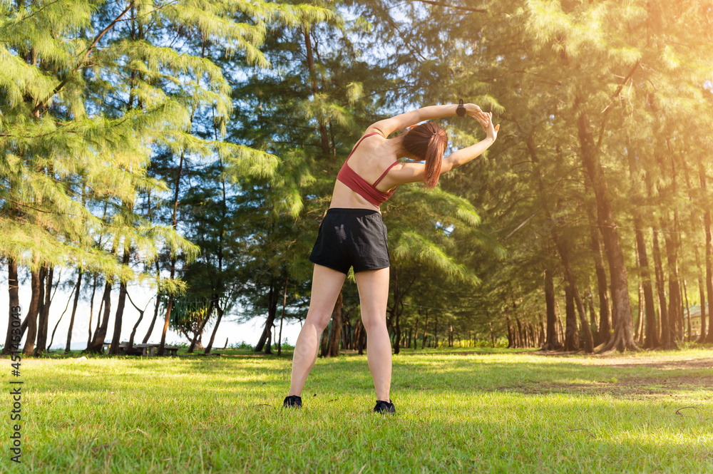 亚洲运动型女性早上在海滩公园锻炼和伸展身体