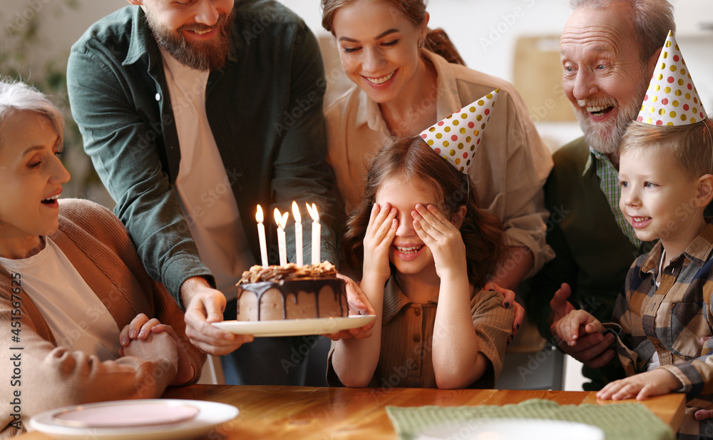 快乐的大家庭带来了点燃蜡烛的生日巧克力蛋糕，让兴奋的小女孩大吃一惊