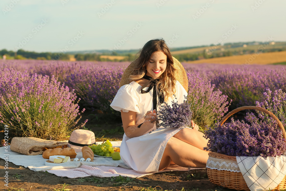 美丽的年轻女子在薰衣草地野餐