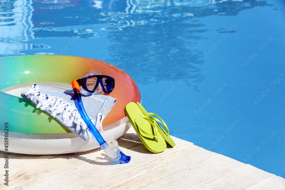 游泳池边缘的充气环、毛巾、人字拖、浮潜面罩和管子，特写