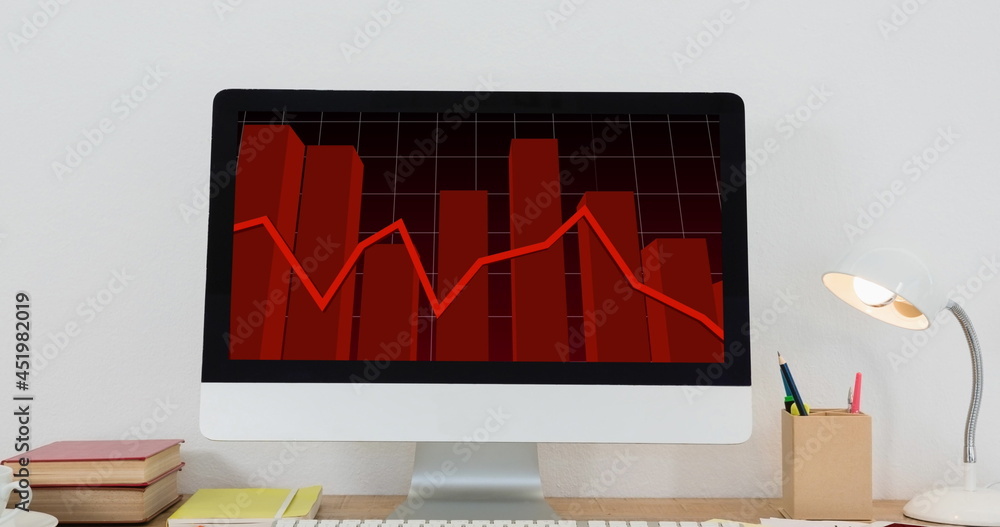 办公桌上电脑屏幕上有红线的财务数据处理图像