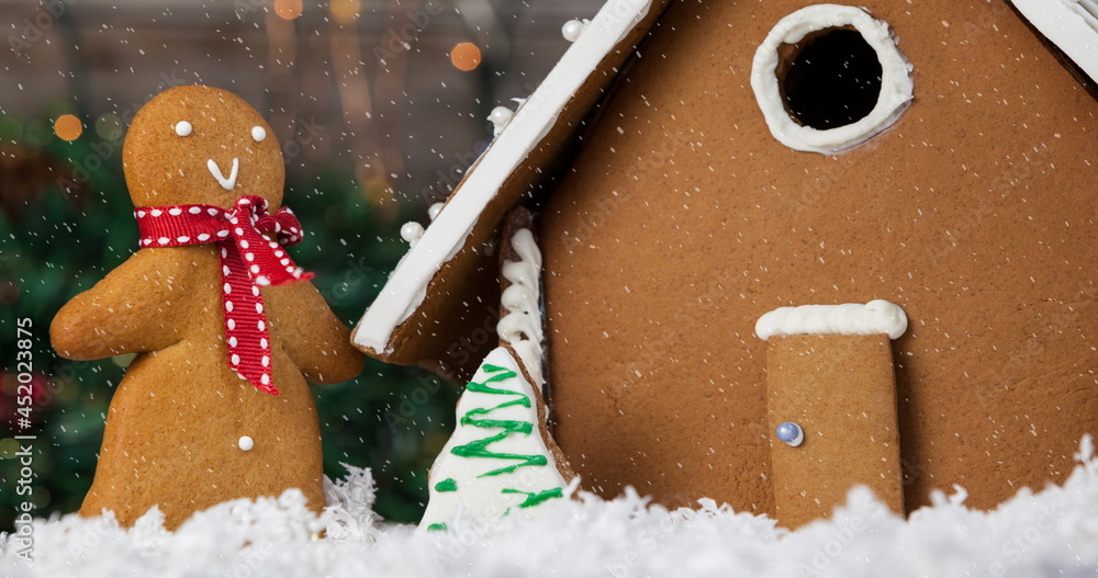 Image of christmas gingerbread snowman and house with snow falling