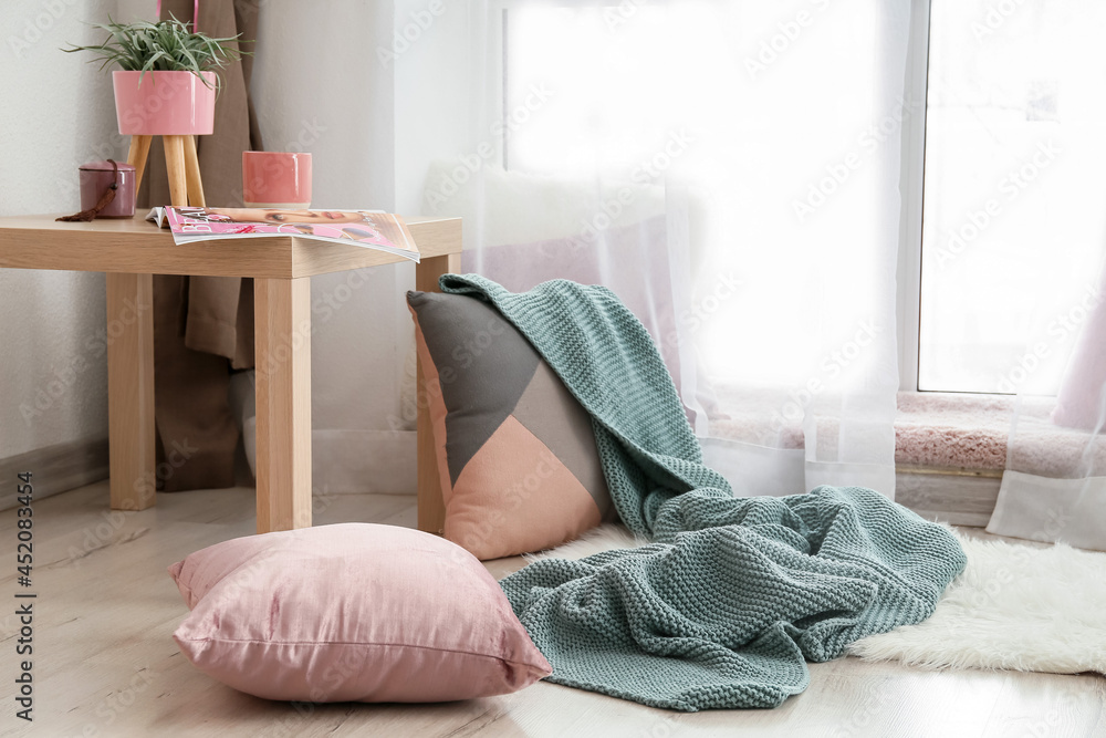 舒适的休息场所，靠近窗户，配有枕头和编织格子布
