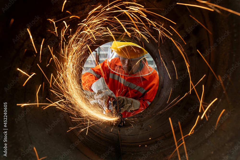An Electric wheel grinding at Industrial worker cutting metal pipe with many sharp sparks