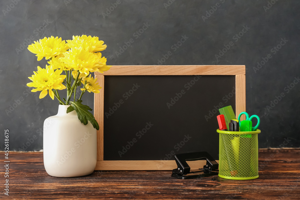 木桌上摆满鲜花、文具和黑板的花瓶。教师节庆祝活动