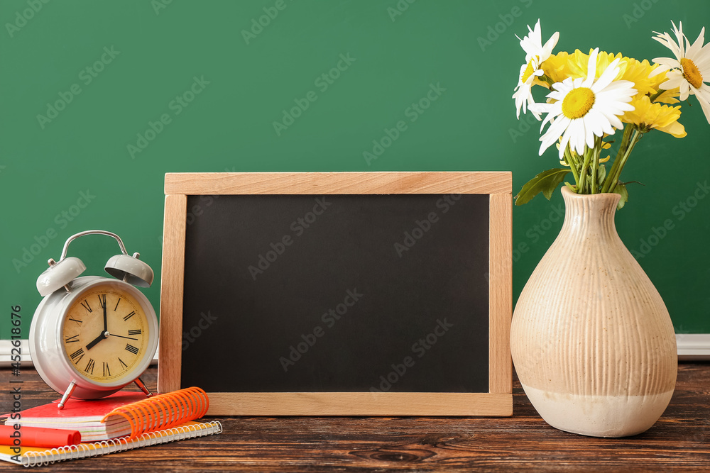 木桌上放着鲜花、文具和黑板的花瓶。教师节庆祝活动