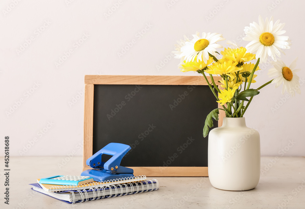 浅背景花瓶，花瓶里有鲜花、文具和黑板。教师节庆祝活动