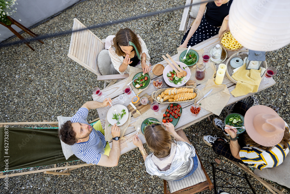 一群朋友在装饰精美的木桌旁用餐，桌上摆满了健康食品，野餐吧