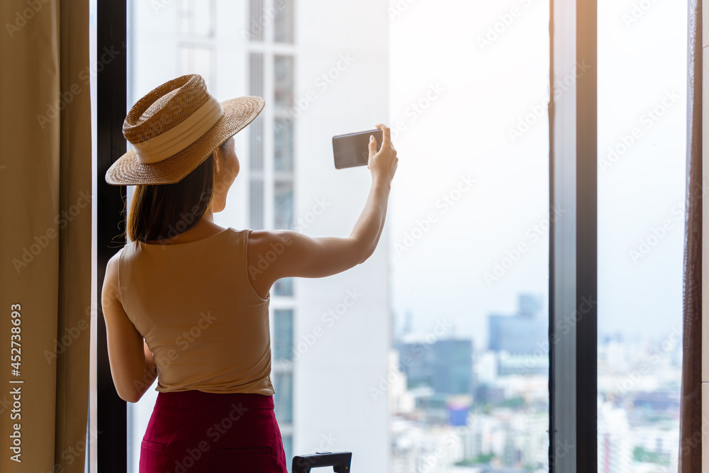 Portrait rear view of woman standing photograph the view close to the window, looking outside in hot