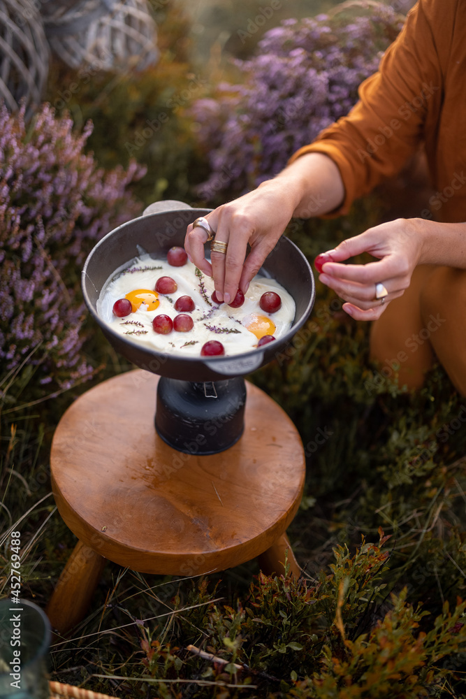 女旅行者在山上旅行时准备早餐，在炉子上煎鸡蛋和葡萄o