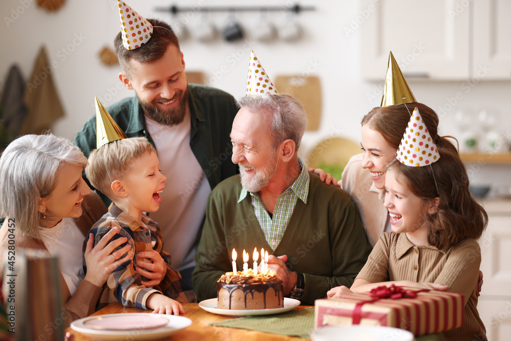 快乐的高加索大家庭戴着派对帽在室内庆祝祖父的生日