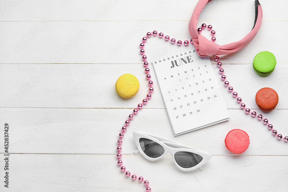 Calendar with macaroons and female accessories on light wooden background