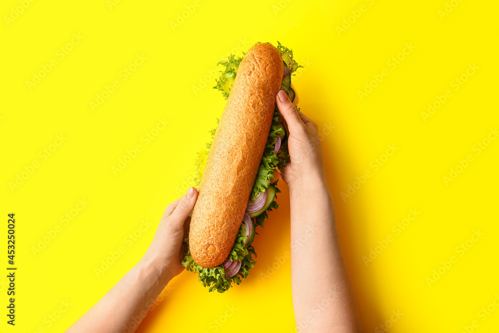彩色背景上有美味三明治的女性手