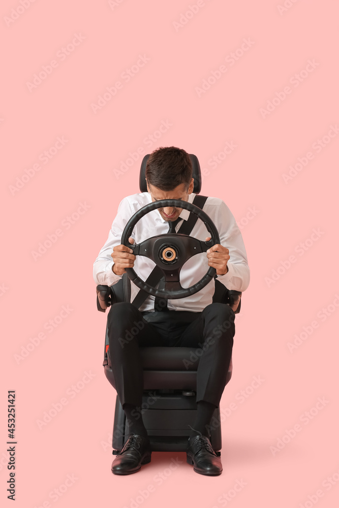 坐在汽车座椅上，彩色背景上有方向盘的压力商人