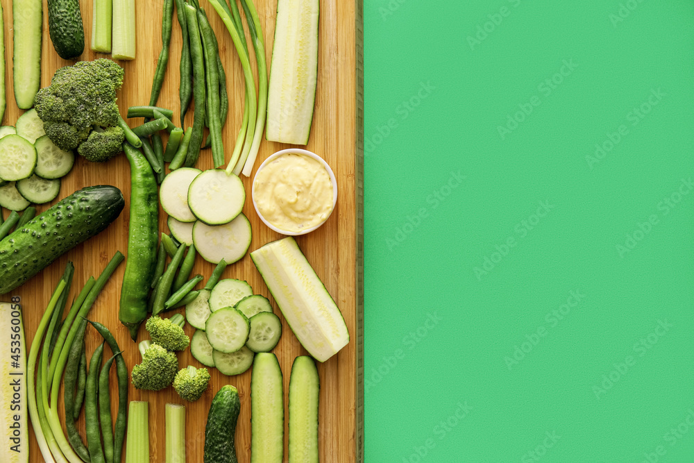 有不同绿色蔬菜的盘子和颜色背景上有酱汁的碗