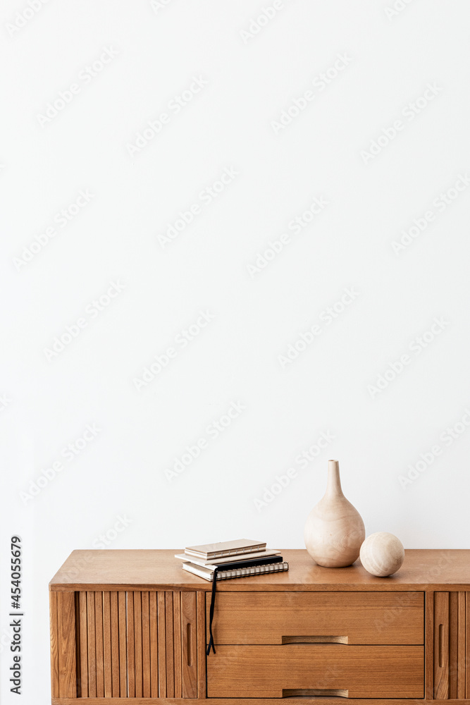 白色房间木橱柜上的一个木制花瓶旁的一堆笔记本