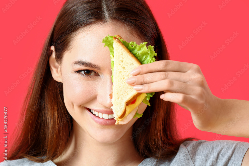 年轻女人，彩色背景上有美味的三明治