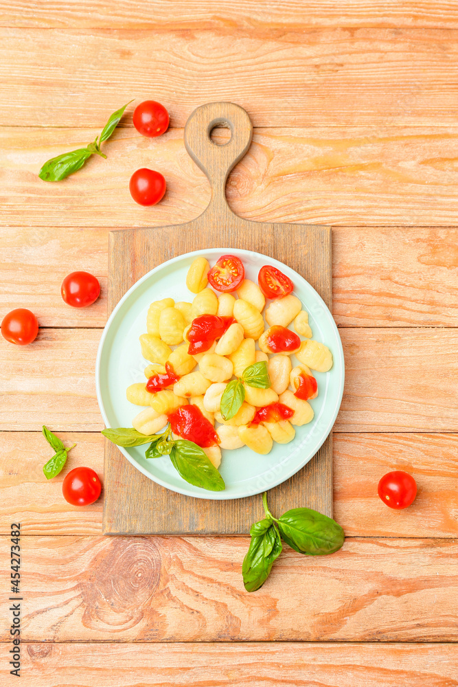Delicious gnocchi with tomato sauce in plate on wooden background