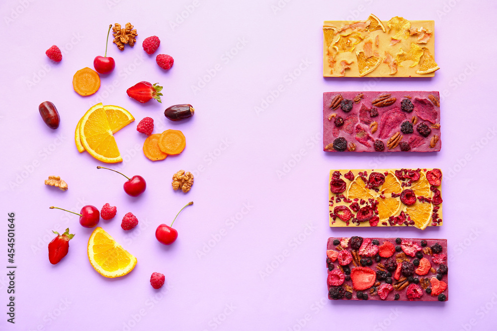Handmade chocolate bars with fruits, berries and nuts on color background