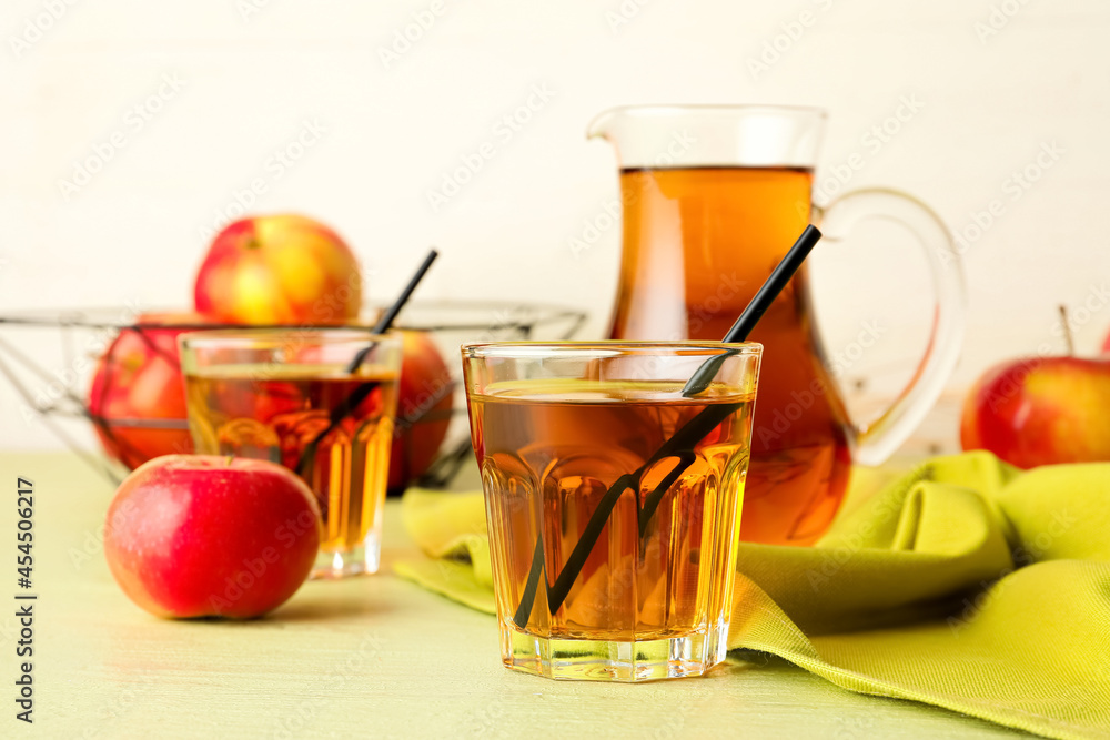 彩色木桌上的一壶一杯美味的苹果汁