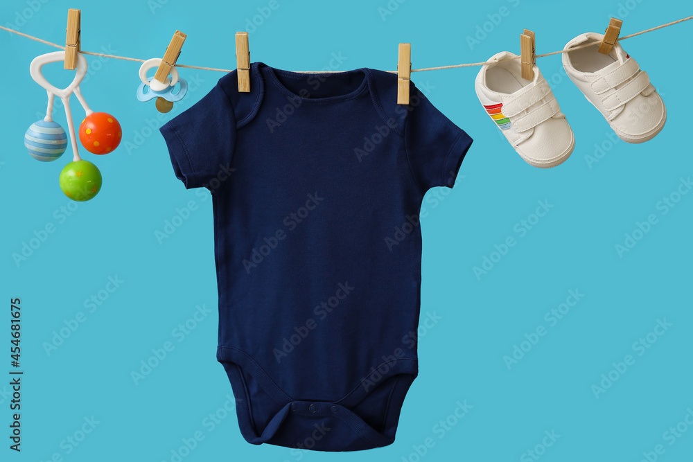 彩色背景下挂在绳子上的婴儿衣服、鞋子、奶嘴和玩具
