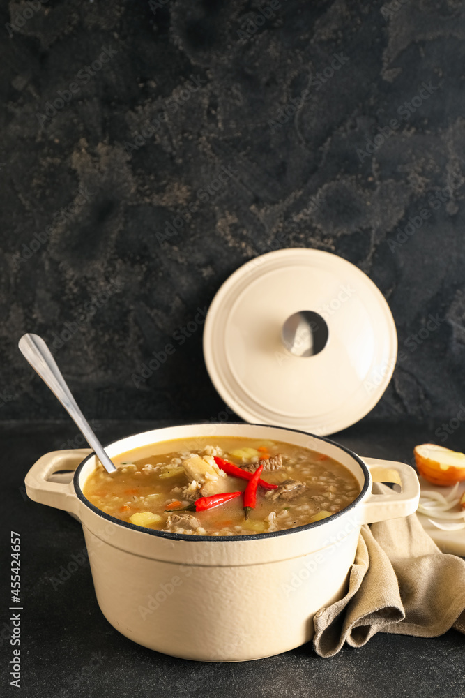 Cooking pot with tasty beef barley soup on table