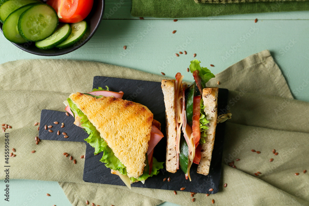彩色木质背景上的美味三明治板