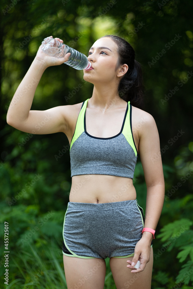 一名口渴的亚洲女运动员在锻炼后喝水。