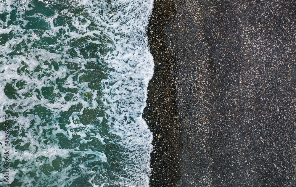海浪拍打着黑色沙滩和卵石，空中自然背景