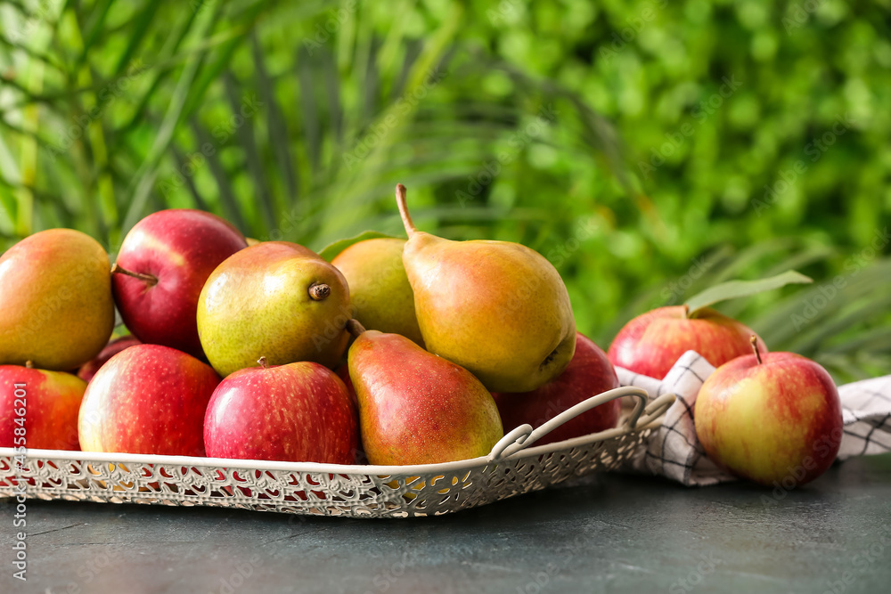 户外桌子上放着成熟的梨和苹果的托盘，特写