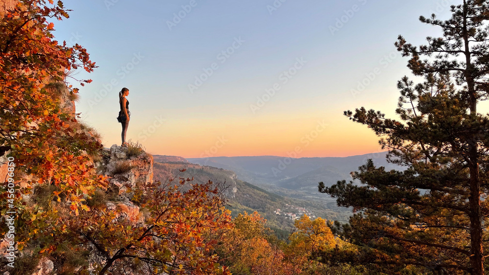 复制空间：年轻女子攀岩从悬崖顶上观察日落。