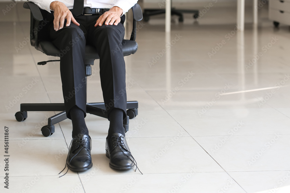 鞋带解开的商人坐在办公室的椅子上