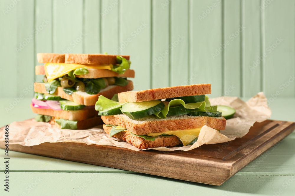 Board with tasty sandwiches on color wooden background