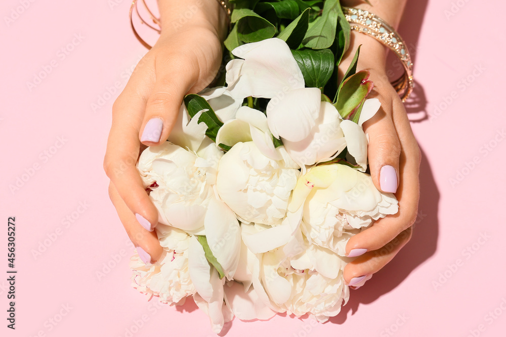 修指甲很漂亮，戴着时尚珠宝的女人在彩色背景上拿着花