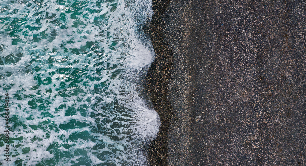 黑色沙滩上有白色海洋泡沫的戏剧性惊涛骇浪，空中海洋纹理