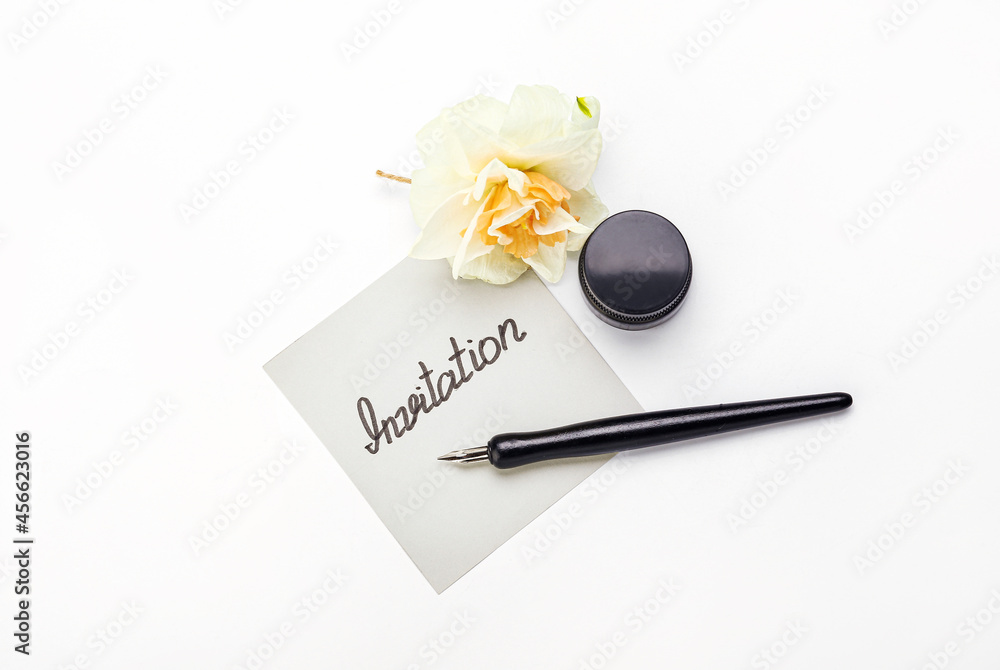 Paper with word INVITATION, nib pen and flower on white background