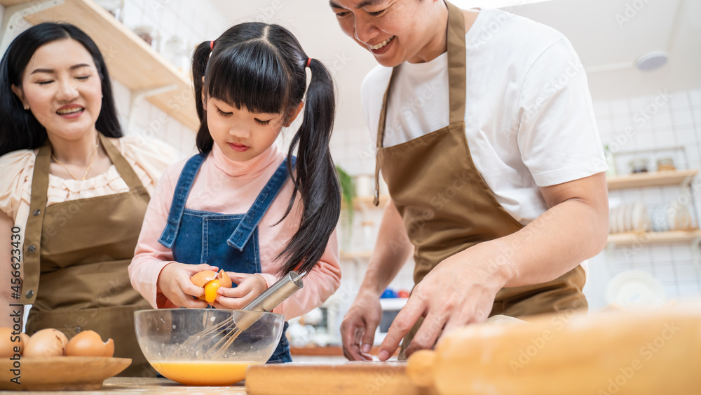 亚洲幸福家庭待在家里的厨房里，和孩子一起烤面包和食物。